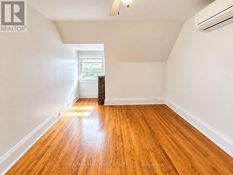 A room with wooden floors and a window with curtains.
