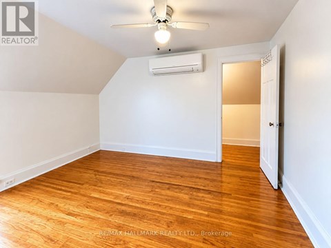 A room with a ceiling fan and wooden flooring.
