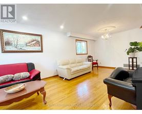 A living room with a red couch, a white couch, and a painting on the wall.