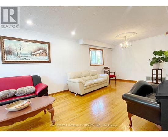 A living room with a red couch, a white couch, and a painting on the wall.