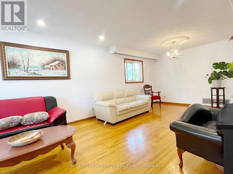 A living room with a red couch, a white couch, and a painting on the wall.