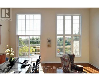 A dining room with a table set for two and a view of a backyard through the windows.