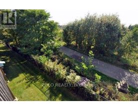 A bird's eye view of a lush green landscape with a pathway and a building on the left.