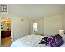 A bedroom with a bed, pillows, and a nightstand with a lamp.