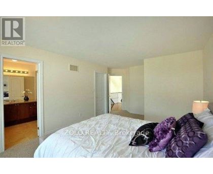 A bedroom with a bed, pillows, and a nightstand with a lamp.