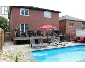 A red umbrella is on a patio with chairs and a pool.