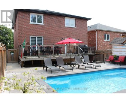 A red umbrella is on a patio with chairs and a pool.