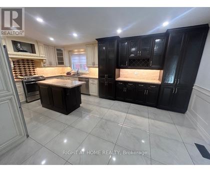 A kitchen with black cabinets and a marble floor.