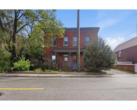 A red brick house with a blue door and a tree in front.