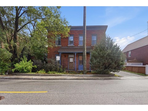 A red brick house with a blue door and a tree in front.