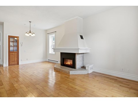 A large, empty room with a fireplace and wooden floors.