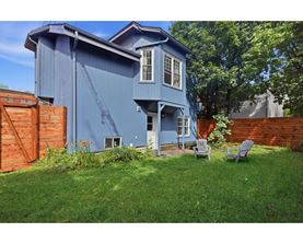A blue house with a white window and a brown fence.