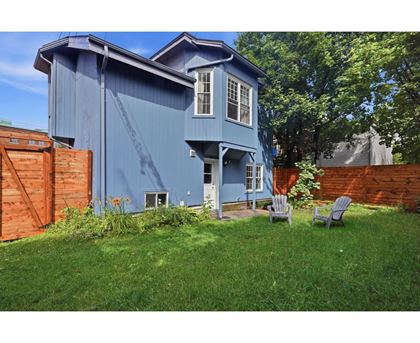 A blue house with a white window and a brown fence.