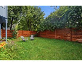 A backyard with a wooden fence and two chairs.