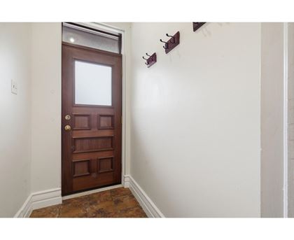 A brown door with a glass window is in a room with white walls.