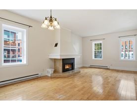 A living room with a fireplace and wooden floors.