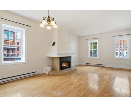 A living room with a fireplace and wooden floors.