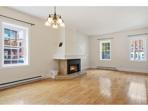 A living room with a fireplace and wooden floors.