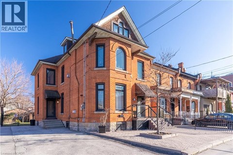 A red brick house with a black car parked in front.