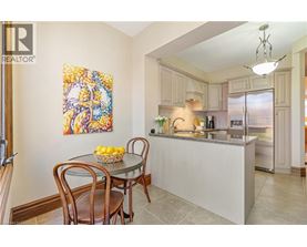 A kitchen with a table and chairs in front of a fridge.