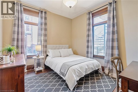 A bedroom with a bed, nightstand, and window with curtains.