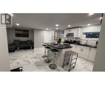 A modern kitchen with a bar stool and a black countertop.