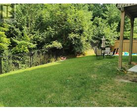 A backyard with a lawn, a fence, and a patio area.