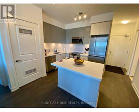 A modern kitchen with a white island and wooden floors.