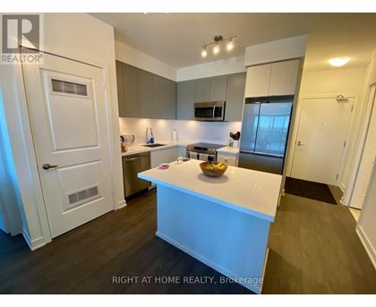 A modern kitchen with a white island and wooden floors.