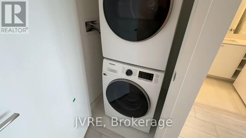 A white washing machine with a black door is in a kitchen.