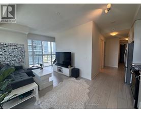 A living room with a television, a couch, and a rug.