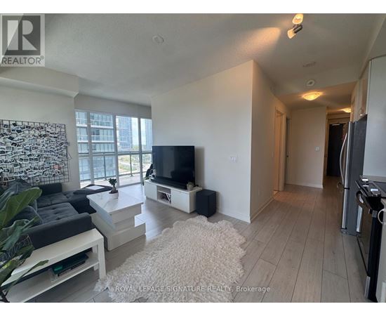 A living room with a television, a couch, and a rug.
