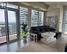 A living room with a couch, coffee table, and a large window overlooking a cityscape.