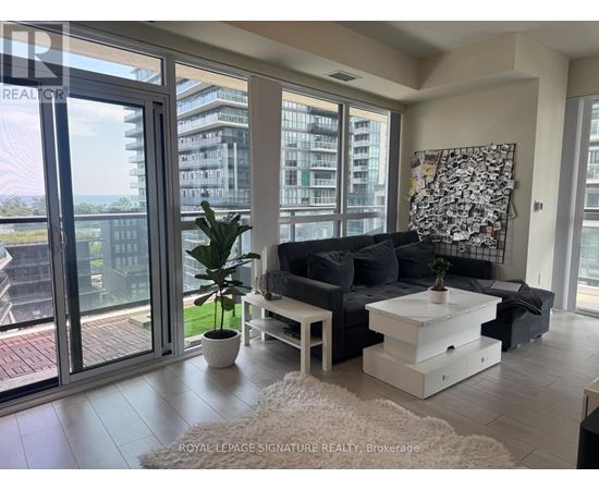 A living room with a couch, coffee table, and a large window overlooking a cityscape.