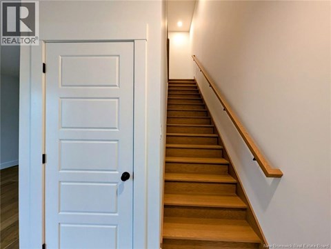A white door is on the left of a staircase.