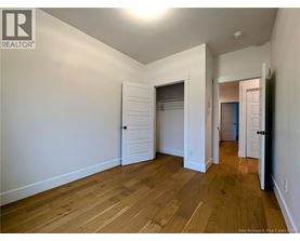 A room with wooden floors and white walls, with a door on the right side.