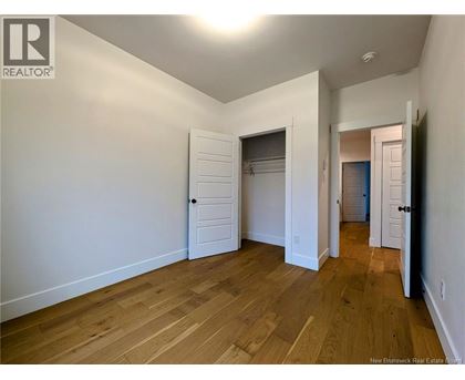 A room with wooden floors and white walls, with a door on the right side.
