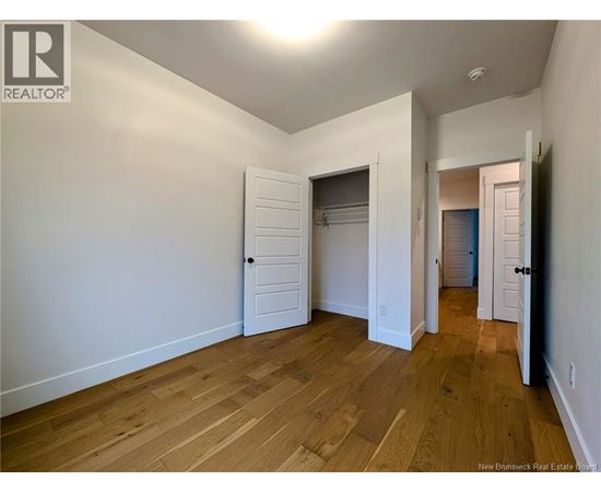 A room with wooden floors and white walls, with a door on the right side.