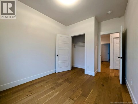 A room with wooden floors and white walls, with a door on the right side.