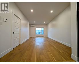 A spacious room with wooden flooring and white walls.