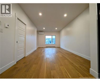A spacious room with wooden flooring and white walls.