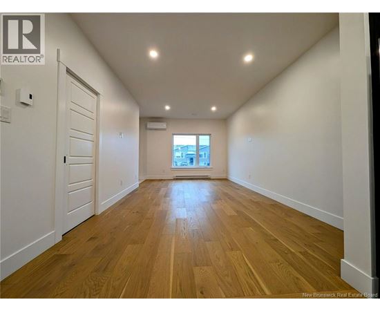 A spacious room with wooden flooring and white walls.
