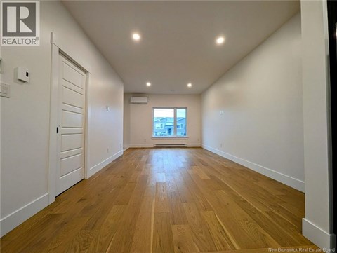 A spacious room with wooden flooring and white walls.
