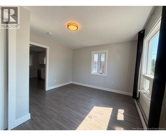 A room with a window and a door leading to another room.