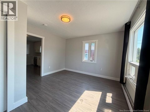 A room with a window and a door leading to another room.