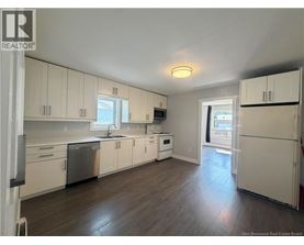 A kitchen with white cabinets and a wooden floor.