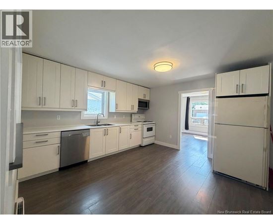 A kitchen with white cabinets and a wooden floor.