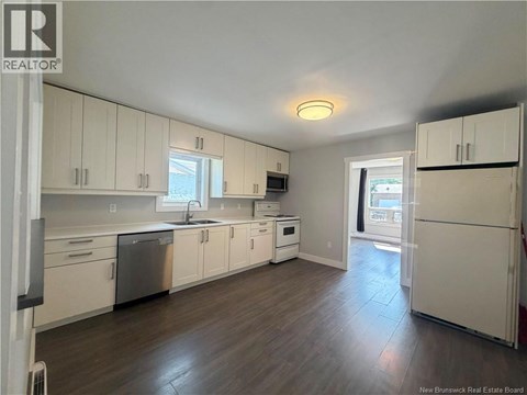 A kitchen with white cabinets and a wooden floor.