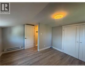A room with a wooden floor and white walls, with a door on the left and a cabinet on the right.