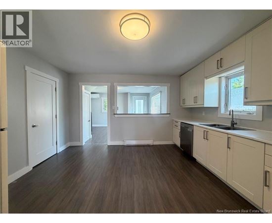 A spacious kitchen with white cabinets and a wooden floor.